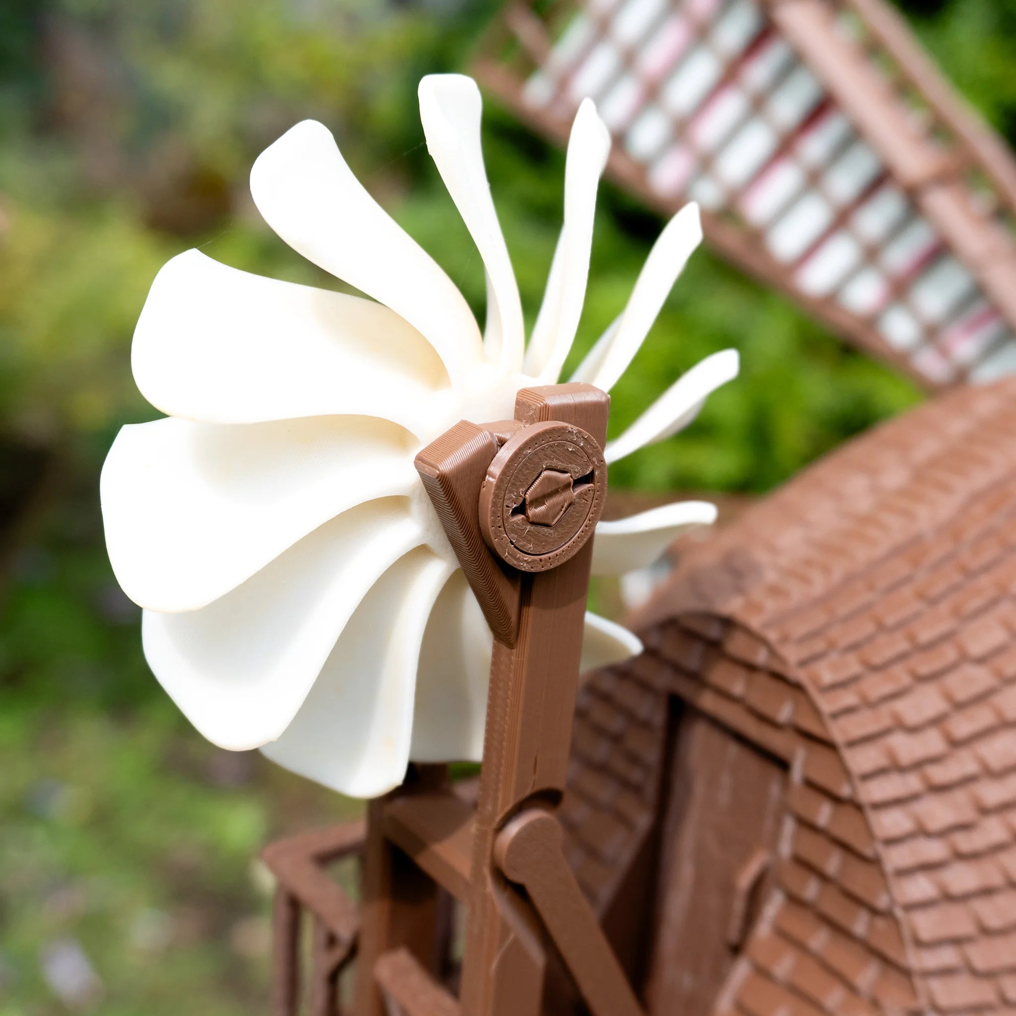 3D-gedruckte Mühle Jutland Mill Colding mit weißer Blume auf Backsteinmauer